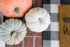 Pumpkins on brick patio with black and white door mat
