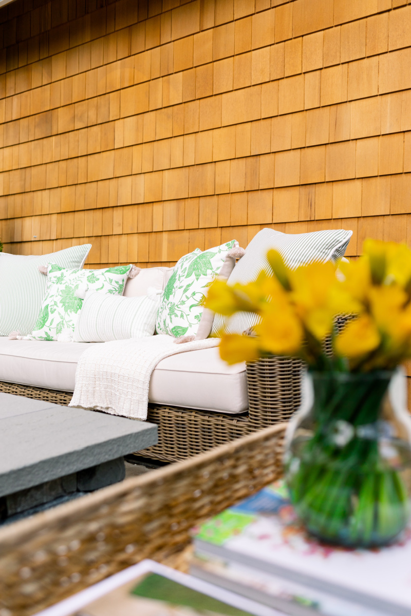 Outdoor sofa and green and white pillows and daffodils