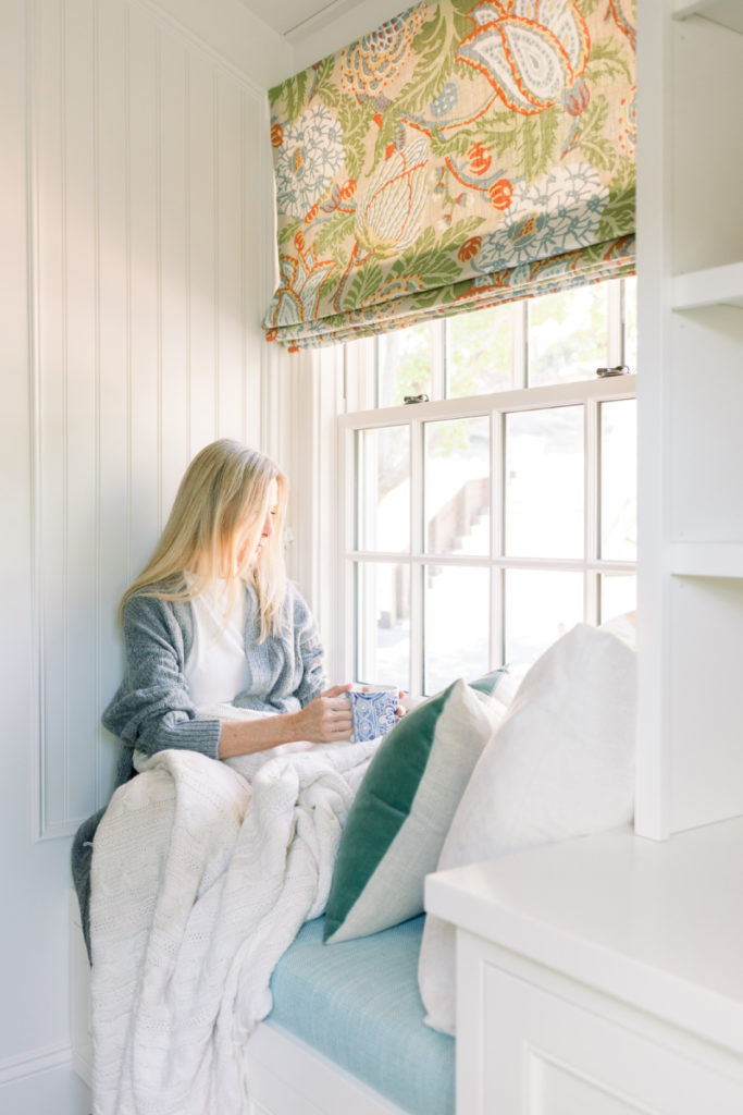 Woman sitting in window seat with throw blanket