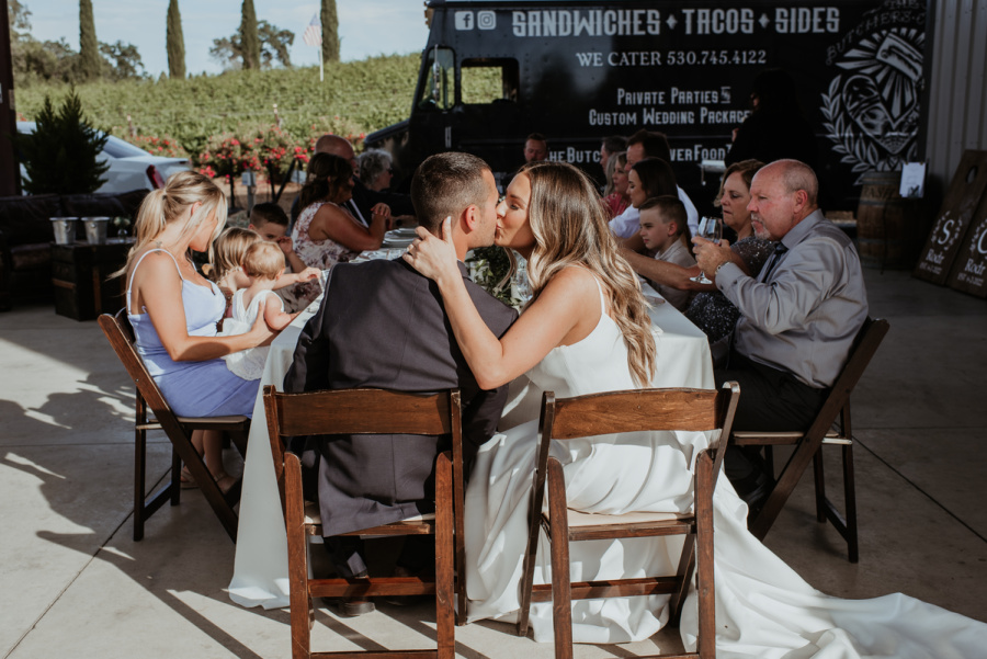 Bride and Groom Kissing at Table