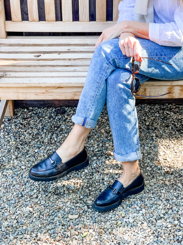 Woman sitting on bench wearing loafers.