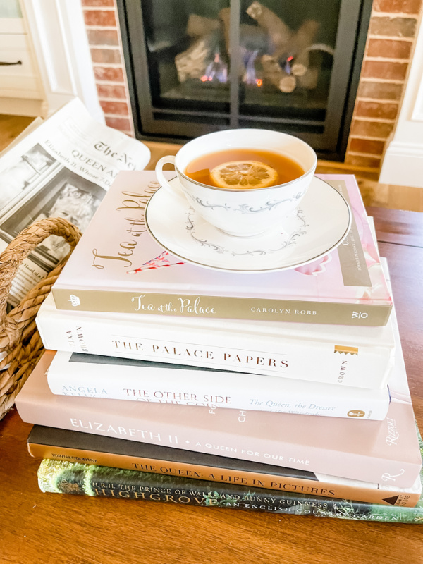 Stack of royal books in front of fireplace with tea cup on top.
