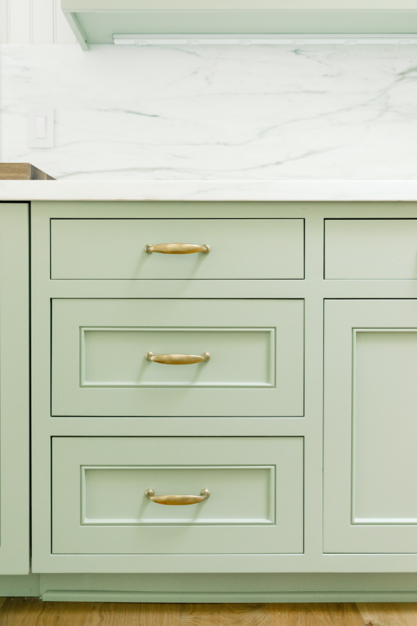 Green kitchen cabinet drawers with gold pulls and Farrow & Ball Vert de Terre paint.