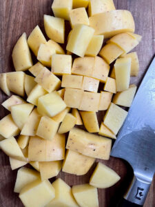 Cubed Yukon gold potatoes on a cutting board.