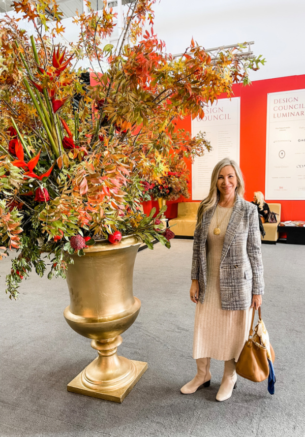 Woman standing next to large urn of branches in convention hal.