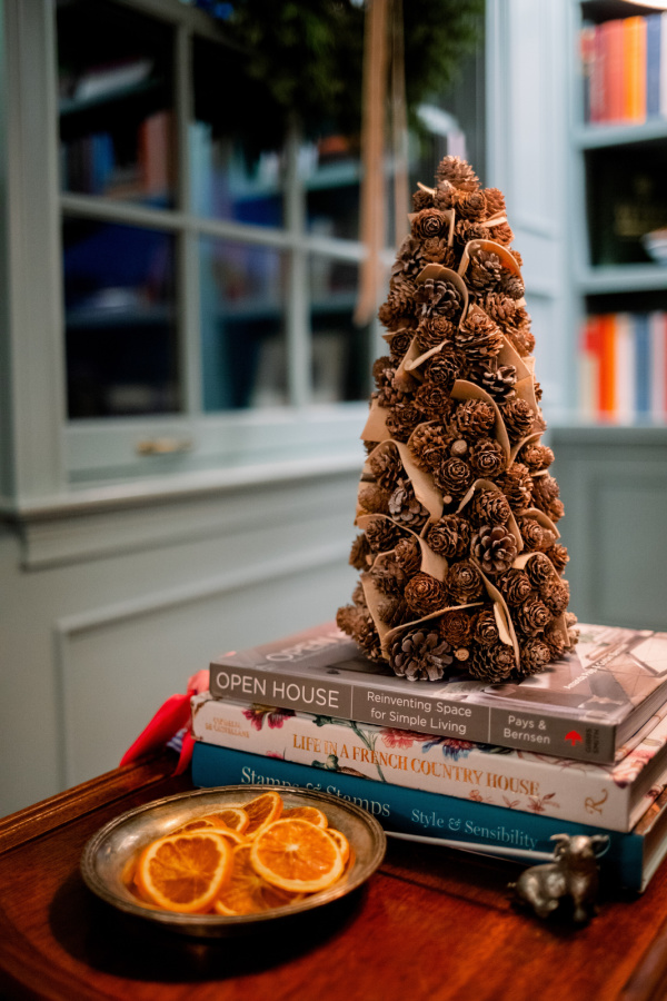 Pinecone tree on stack of books and dish of dried orange slices.