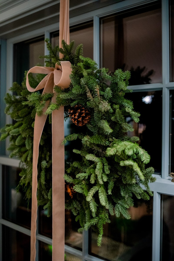 Pine Wreath hung in window with velvet ribbon.
