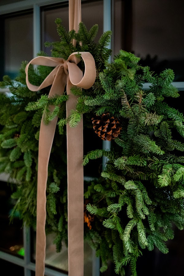 Pine wreath in window hung with velvet ribbon.
