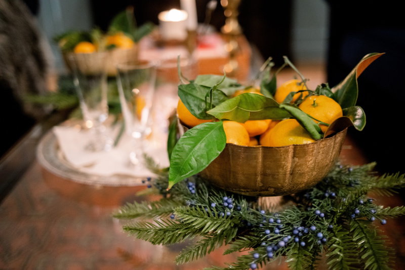 Coffee table adorned for the holidays with pine wreaths and bowls or oranges.