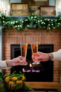 A couple toasting with champagne in front of the fire at Christmas.