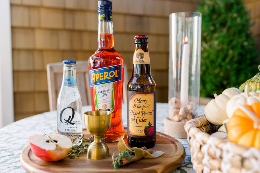 Ingredients on a wooden tray for Apple Cider Aperol Spritzers.