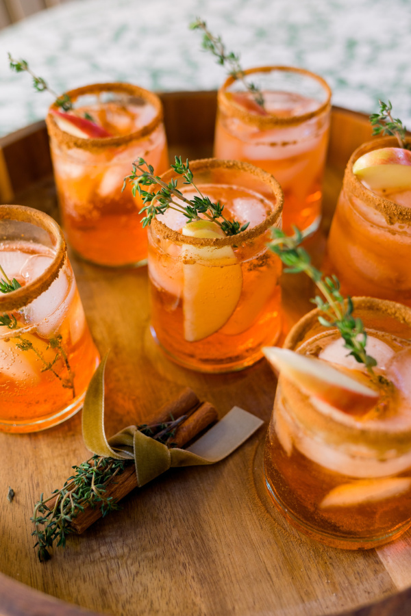 Tray of Apple Cider Aperol Spritzers garnished with thyme and apple slices.