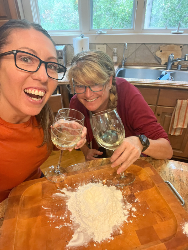Two women drinking wine and making pumpkin ravioli.