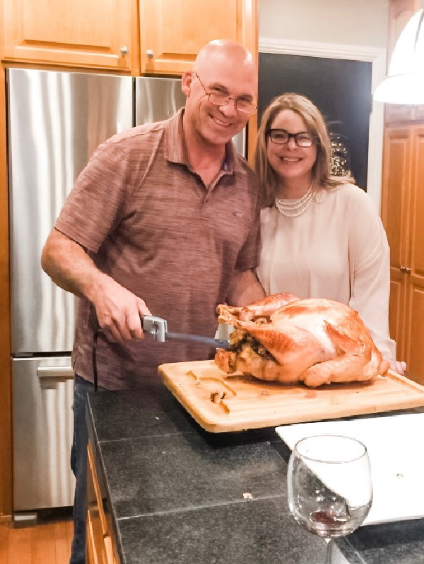 Couple in kitchen carving turkey.