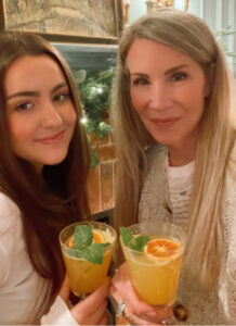woman and her niece saying cheers with orange cocktails.