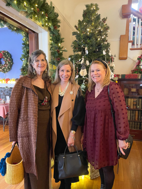 Three woman standing in front of Christmas tree.