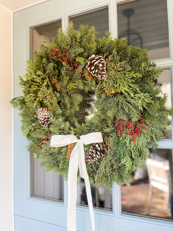 Christmas wreath on front door with white bow.