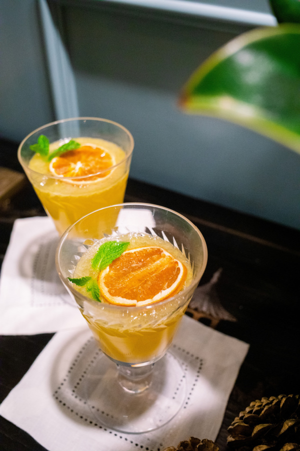 Glasses of Orange Champagne Cocktails on cocktail napkins.
