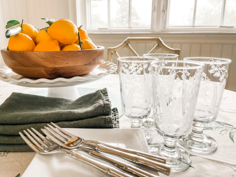 Etched wine glasses, plates and forks on table with lemon centerpiece.