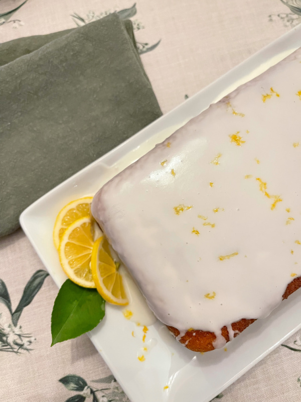 Lemon Cake with glaze on top and slices of lemons on platter.