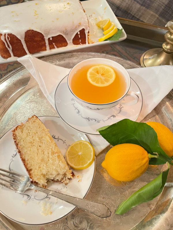 Tea and cake on silver tray with lemons.