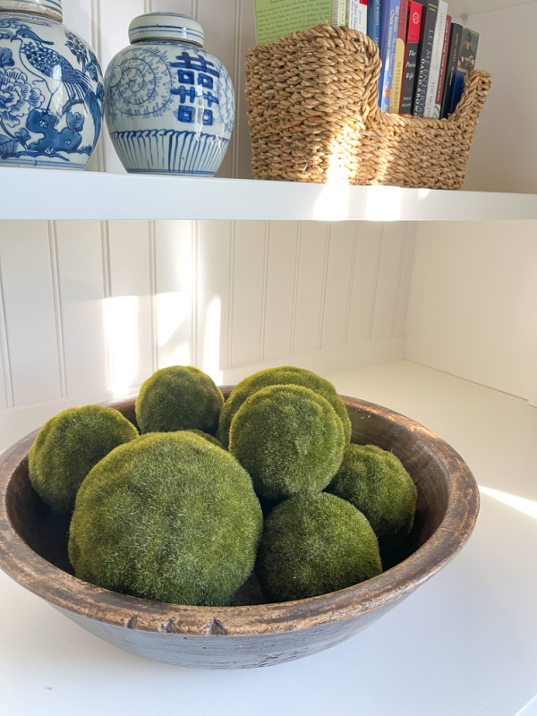 Faux moss balls in large wooden bowl.