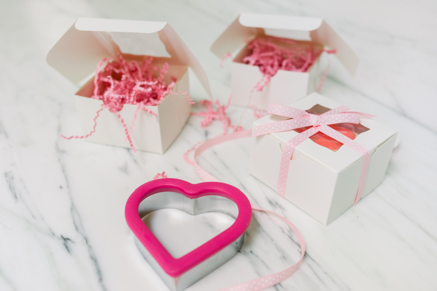 Valentine's Day cookie cutter and boxes with pink confetti.
