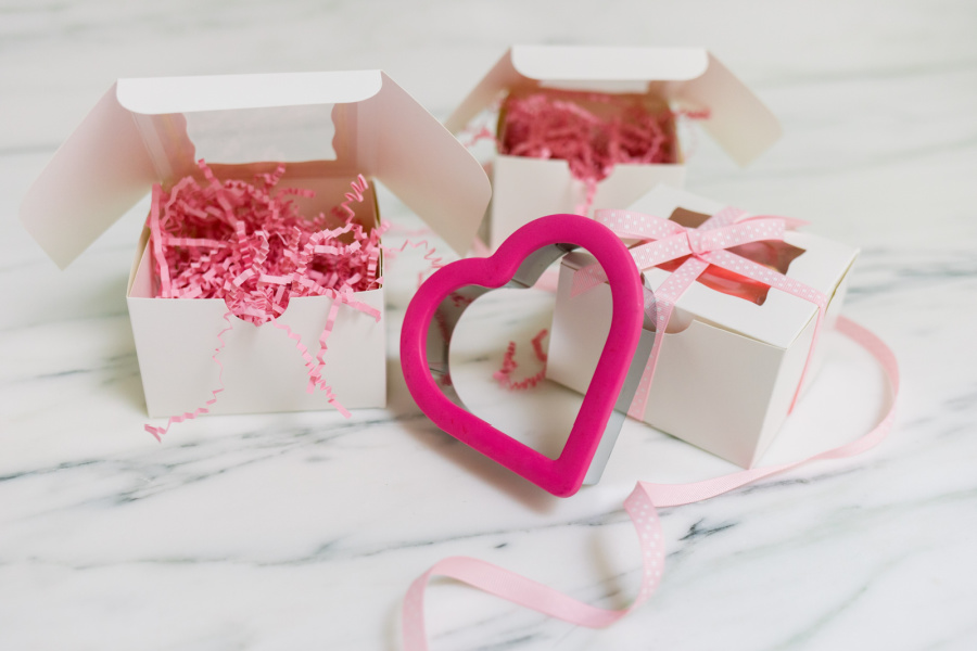 White bakery boxes filled with pink confetti and Valeninte cookies.
