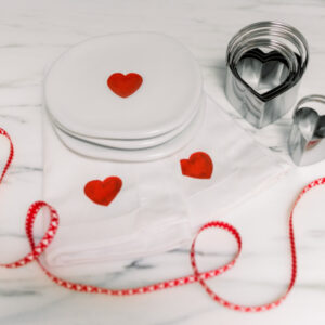 Valentine plates, ribbon and cookie cutters on counter.