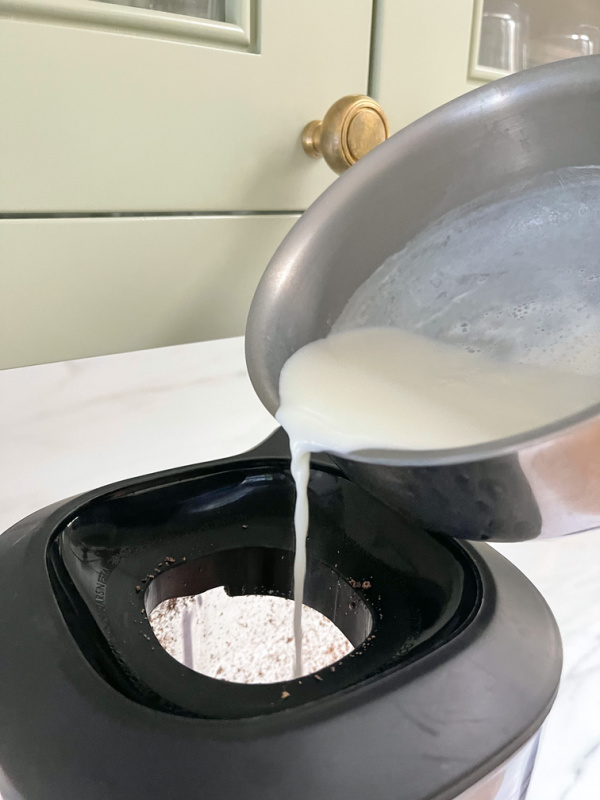 Pouring milk into top of blender.