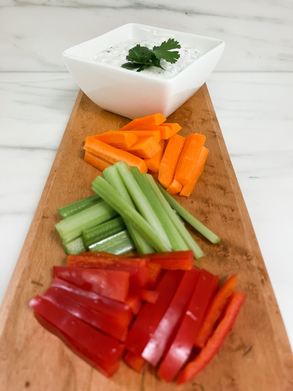 Board of cut vegetables and bowl of dip.