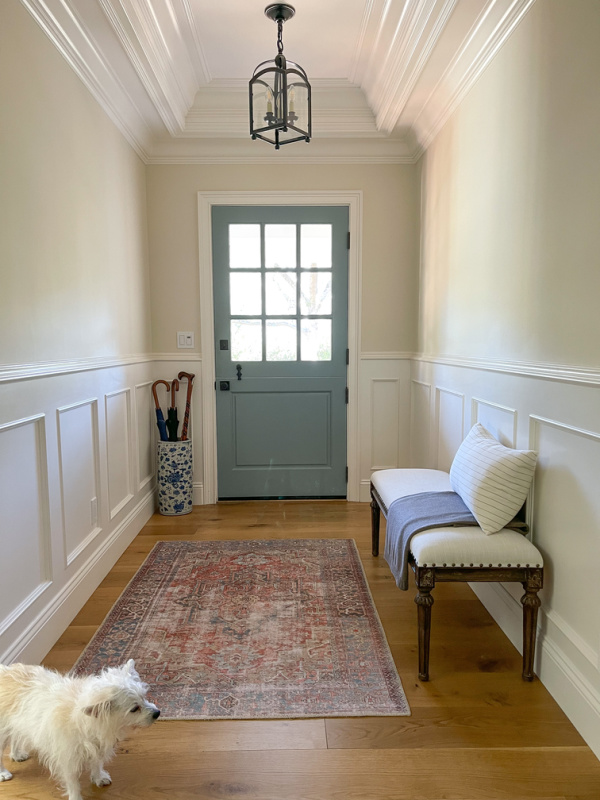 Small foyer with bench, umbrella stand and blue dutch door.