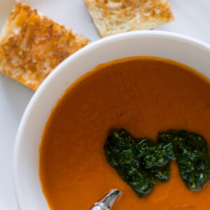 Tomato soup topped with salsa verde and grilled cheese squares.