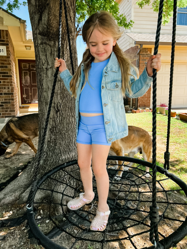 Little girl in denim jacket on swing.