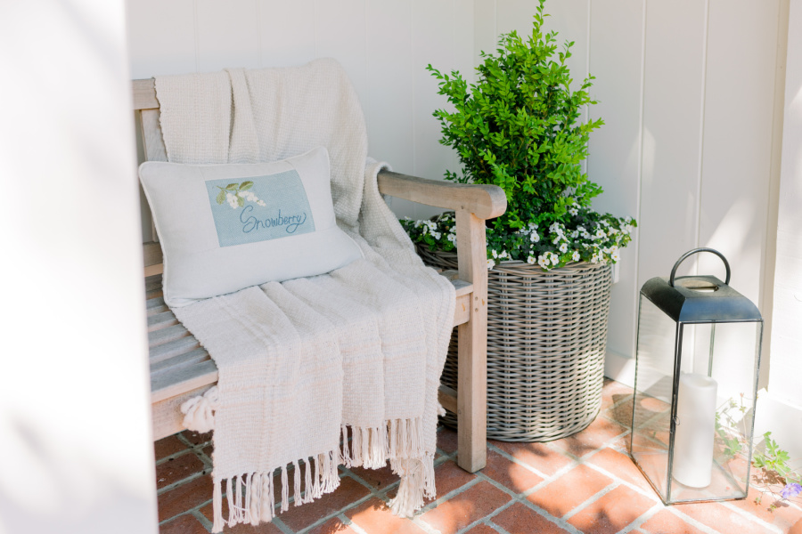 Front porch teak bench with throw blanket and pillow.