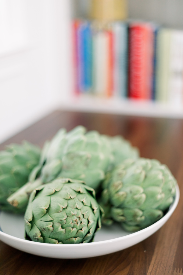 Artichokes in bowl on kitchen counter.