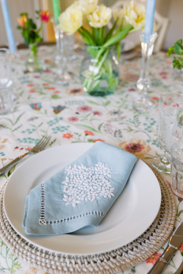 Spring table setting with blue embroidered napkin.