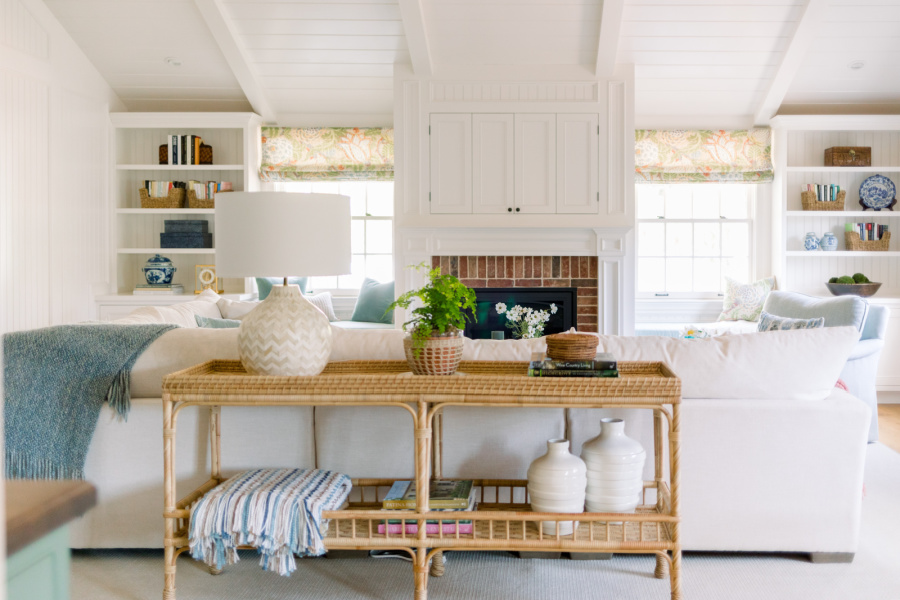 Wide shot of family room with white headboard walls and a pretty woven console table.