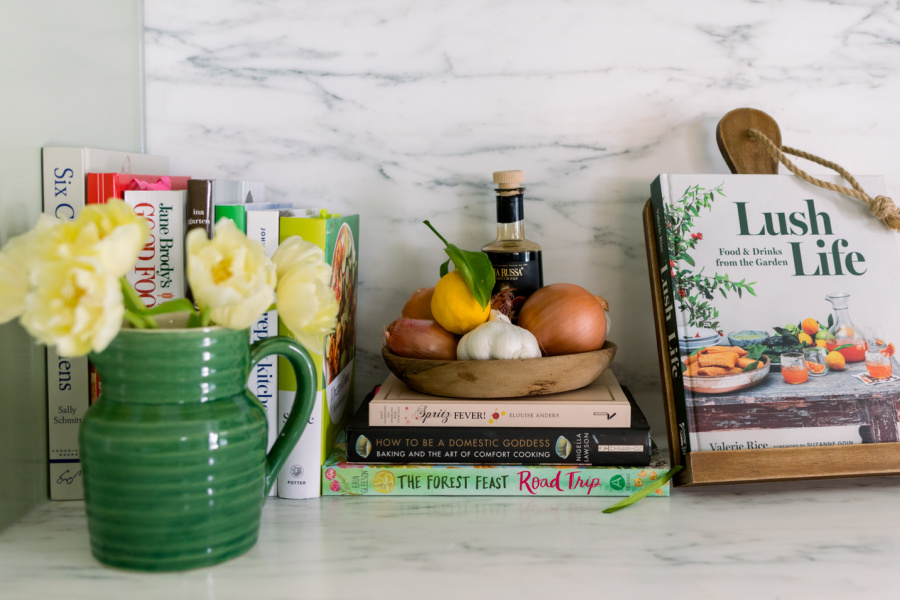 Kitchen counter with cookbooks and a green pitcher filled with tulips.