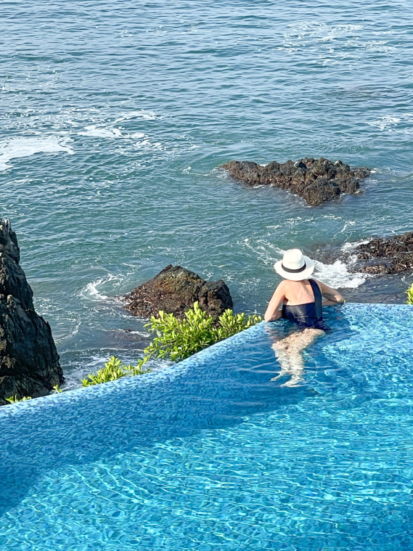Woman in infinity pool overlooking ocean in Zihautanejo.
