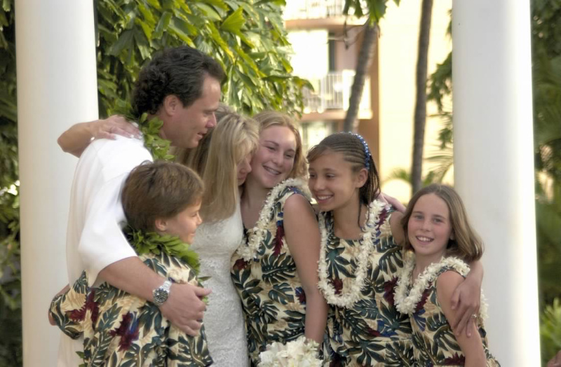 Bride and groom with their four kids hugging after wedding ceremony.