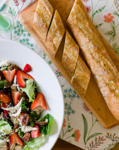 Spring Salad and baguette on embroidered table cloth.