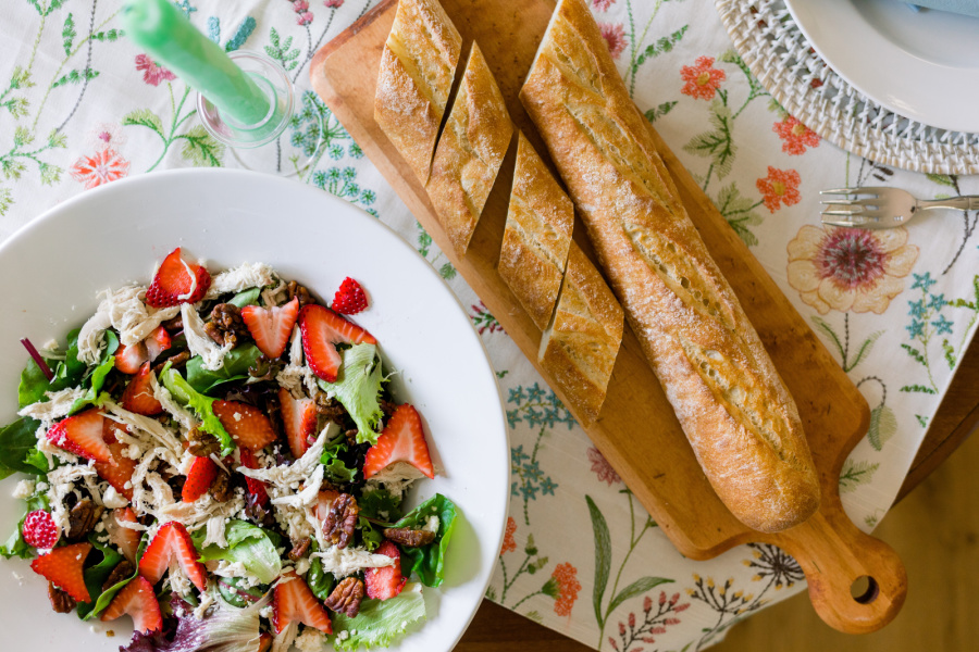 Spring Salad and baguette on embroidered table cloth.