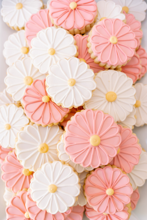 Flower cookies in pink and white on platter at baby shower.