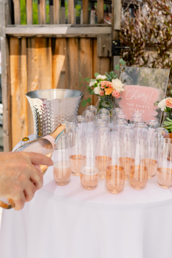 Baby shower welcome drink table, pouring Prosecco into flutes.