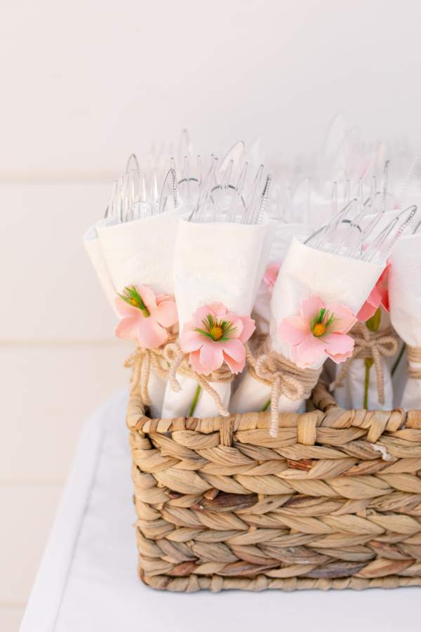 Utensils wrapped in napkins and tied with yarn and faux floral.