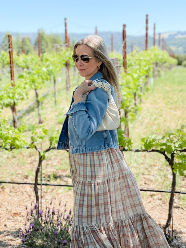 woman wearing summer dress and denim jacket in Napa Valley vineyard.