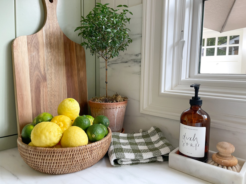Kitchen counter bowl of citrus, topiary and dish soap.