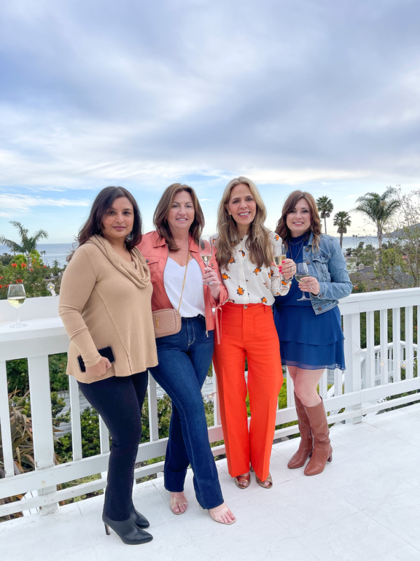 Four women standing on oceanside deck.