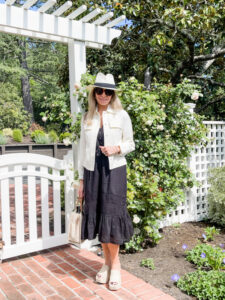 Woman wearing black Rails Kiki dress standing in front of garden gate.